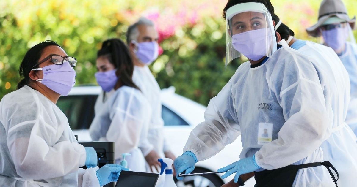 Health-care workers facilitate tests at a drive-in COVID-19 testing center in Los Angeles on Aug. 11, 2020.