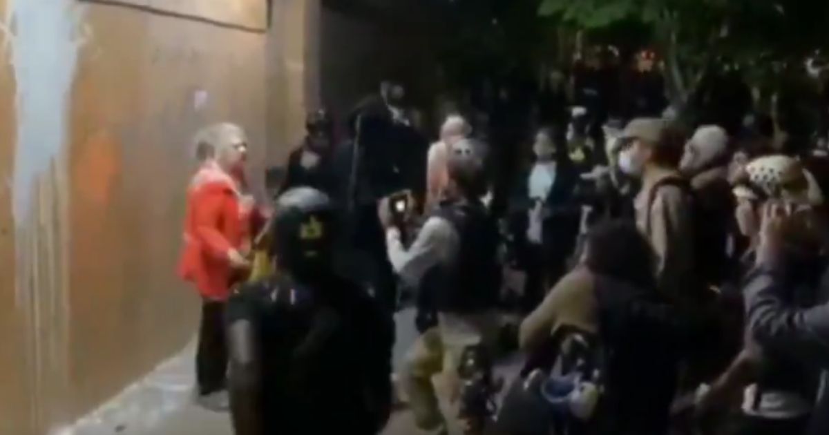 An elderly woman with paint on her face tries to defend a police precinct on another night of violence in Portland, Oregon, on Aug. 6, 2020.