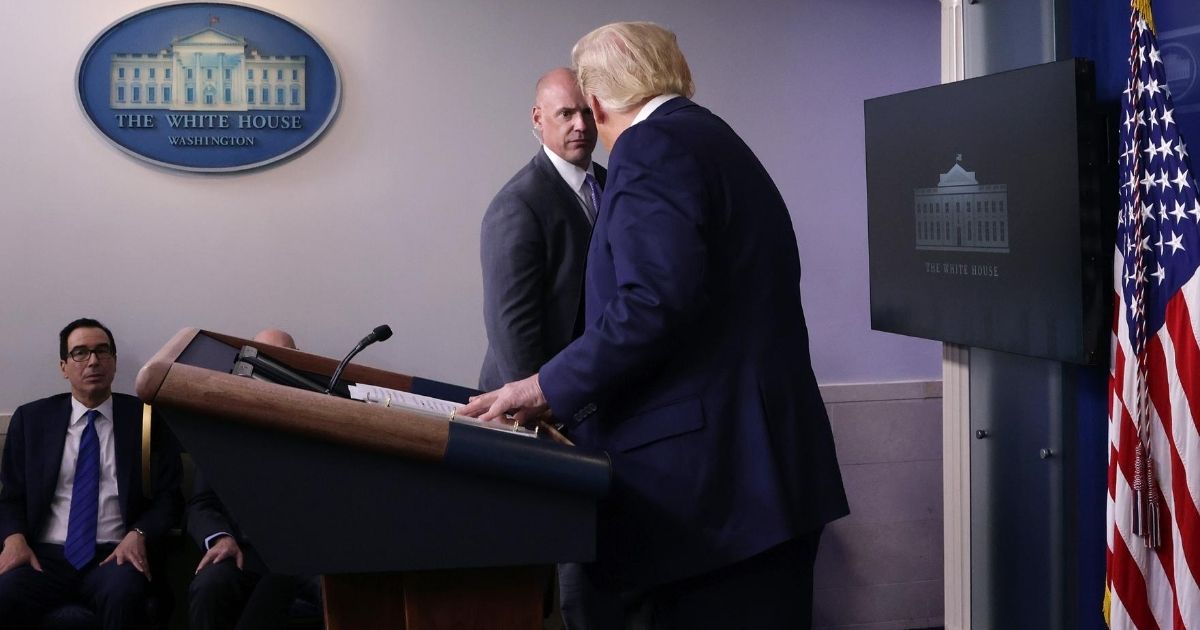 A U.S. Secret Service agent tells President Donald Trump to leave the briefing room after shots were reported fired near the White House on Aug. 10, 2020. Trump briefly stopped his news conference but returned after the all-clear was issued.