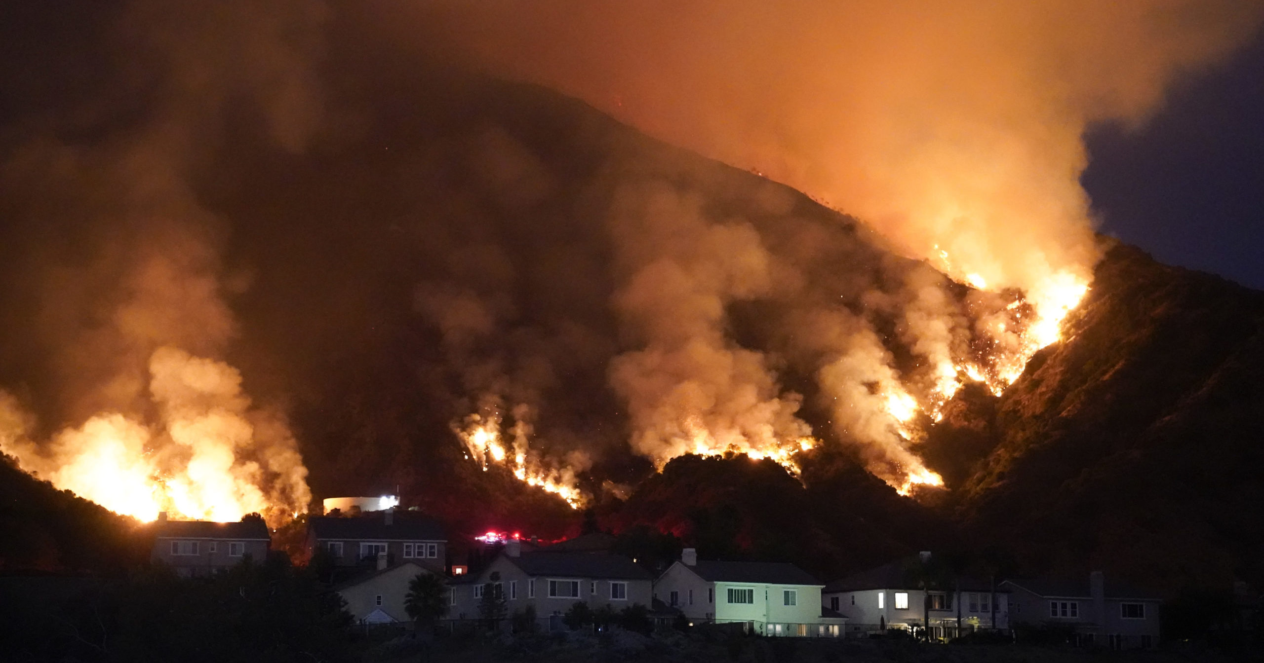 A fire burns through a residential area on Aug. 13, 2020, in Azusa, California. Heat wave conditions were making difficult work for fire crews battling wildfires across Southern California.