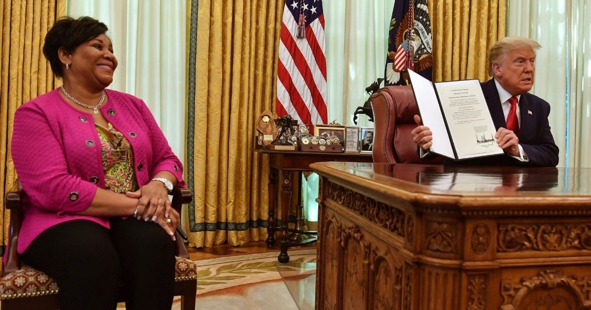 President Donald Trump displays Alice Johnson's full pardon in the Oval Office of the White House in Washington, D.C., on Aug. 28, 2020. Trump granted Johnson, a criminal justice reform advocate and former federal prisoner, a full pardon after commuting her sentence in 2018.