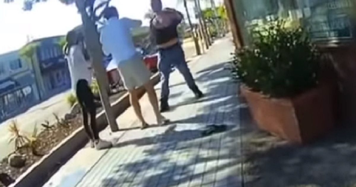 Two men and a woman scuffle on the sidewal in Manhattan Beach, California.