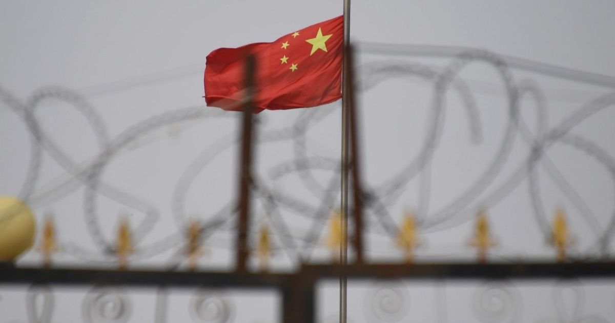This photo taken on June 4, 2019, shows the Chinese flag behind razor wire at a housing compound in Yangisar in China's western Xinjiang region.