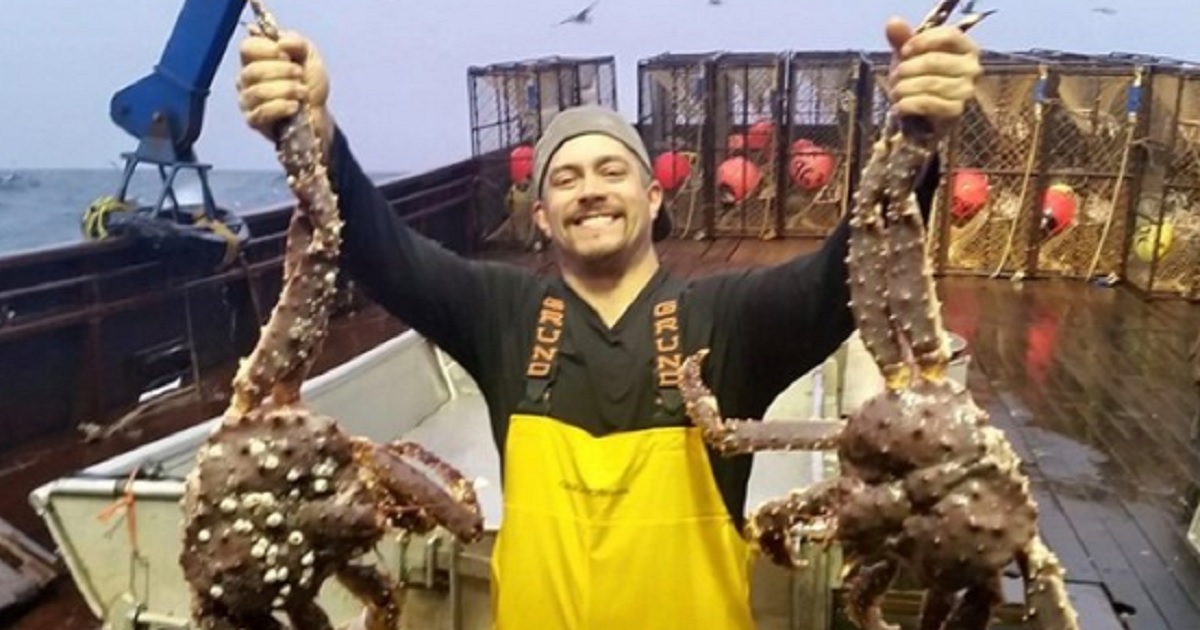 Mahlon Reyes holding an enormous king crab in each hand.