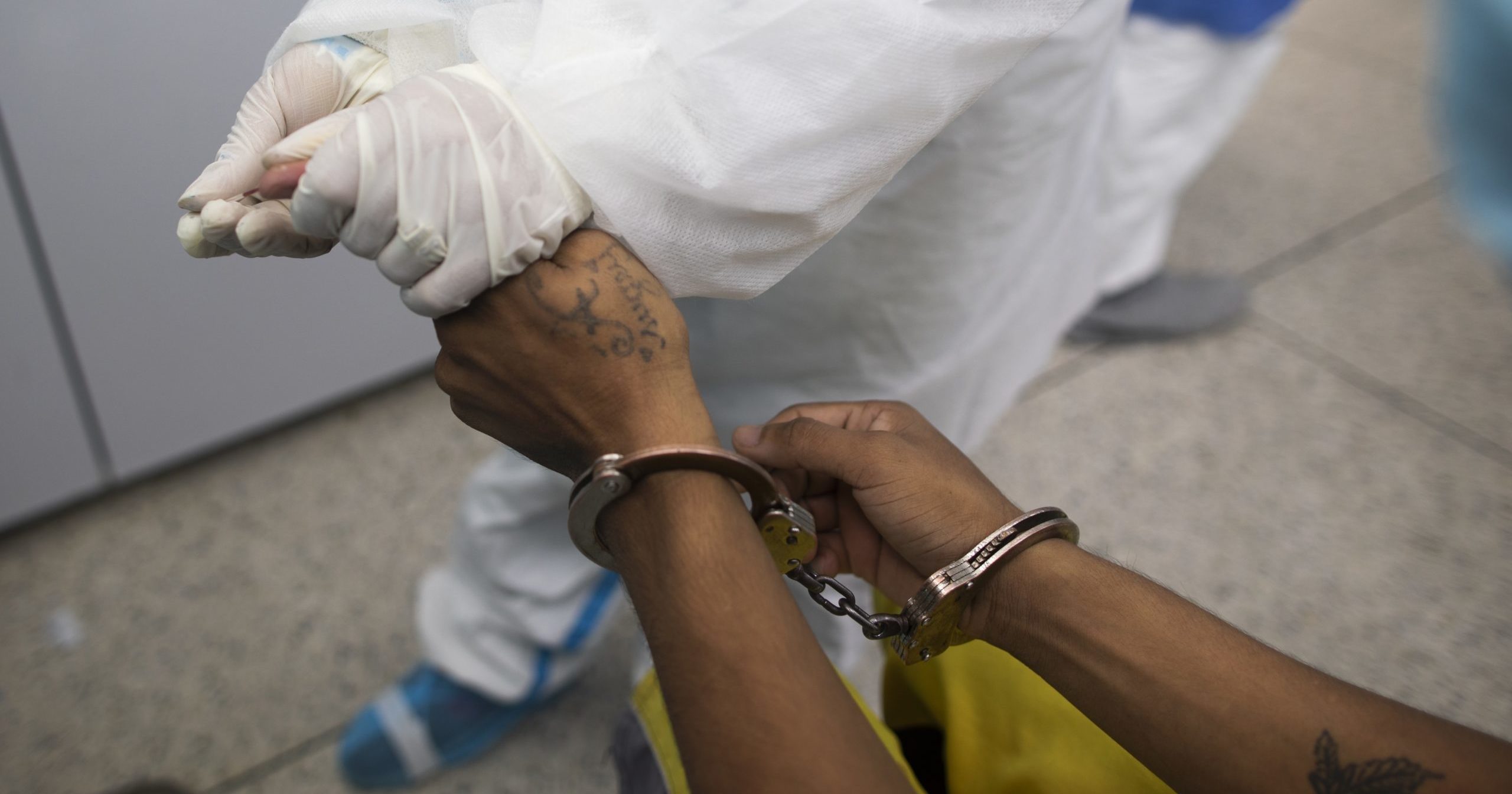 A doctor takes a blood sample for a COVID-19 test from a handcuffed inmate at a diagnosis center in Caracas, Venezuela, on Aug. 27, 2020.