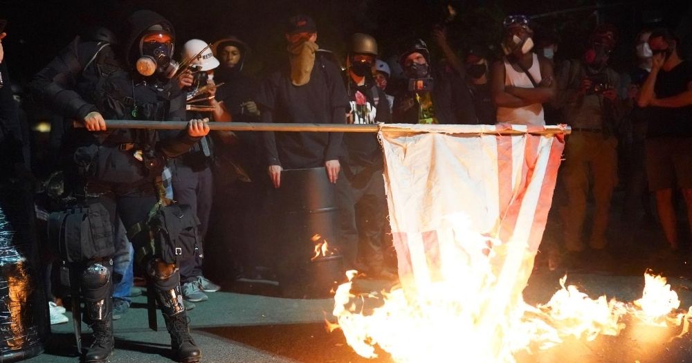 A protester burns an American flag in front of the Mark O. Hatfield U.S. Courthouse in the early morning on Aug. 1, 2020, in Portland, Oregon.