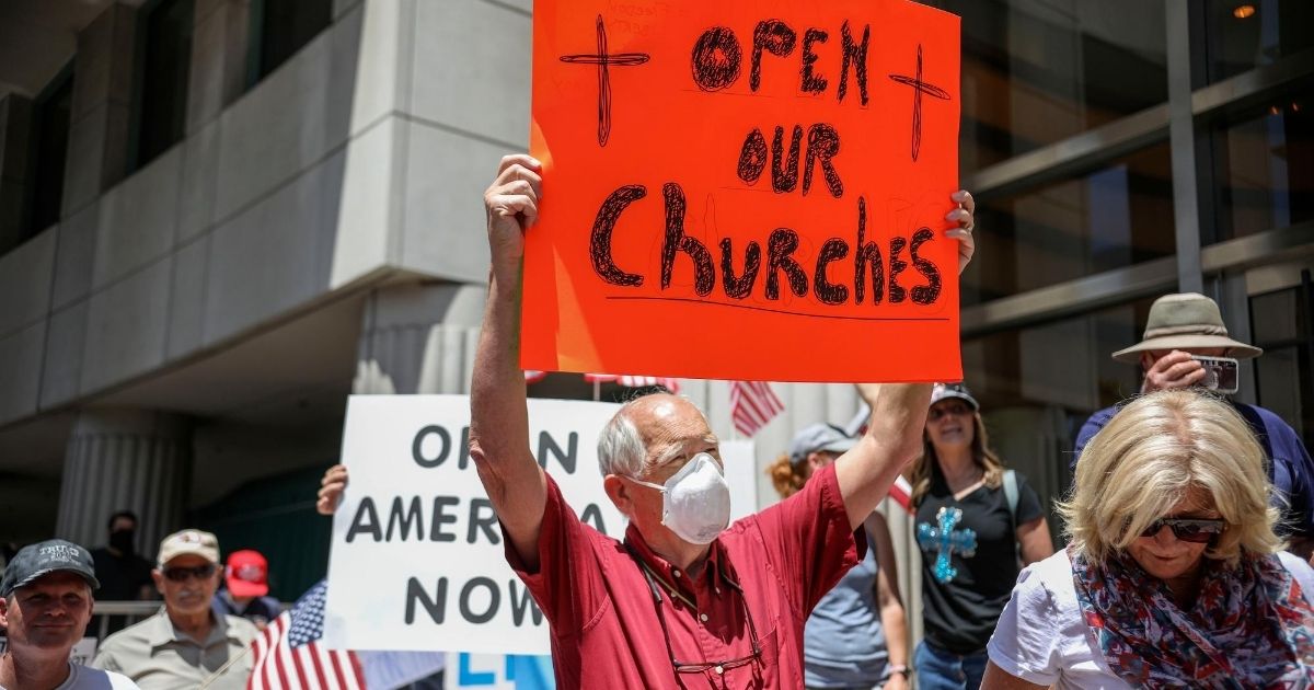 Demonstrators hold signs during a rally to reopen California on May 1, 2020, in San Diego, California.