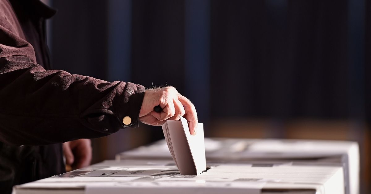 A person casts his ballot in the stock image above.