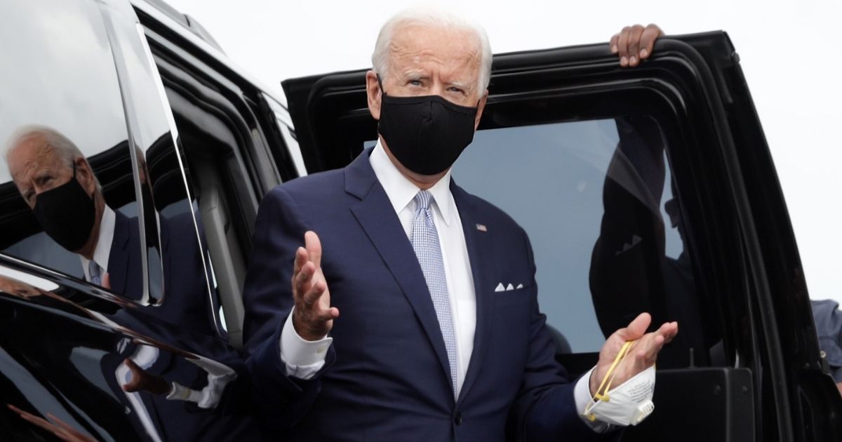 Democratic presidential nominee Joe Biden wears a protective mask on his face while holding another one in his hand as he arrives at the New Castle Airport in Delaware on Aug. 31, 2020.