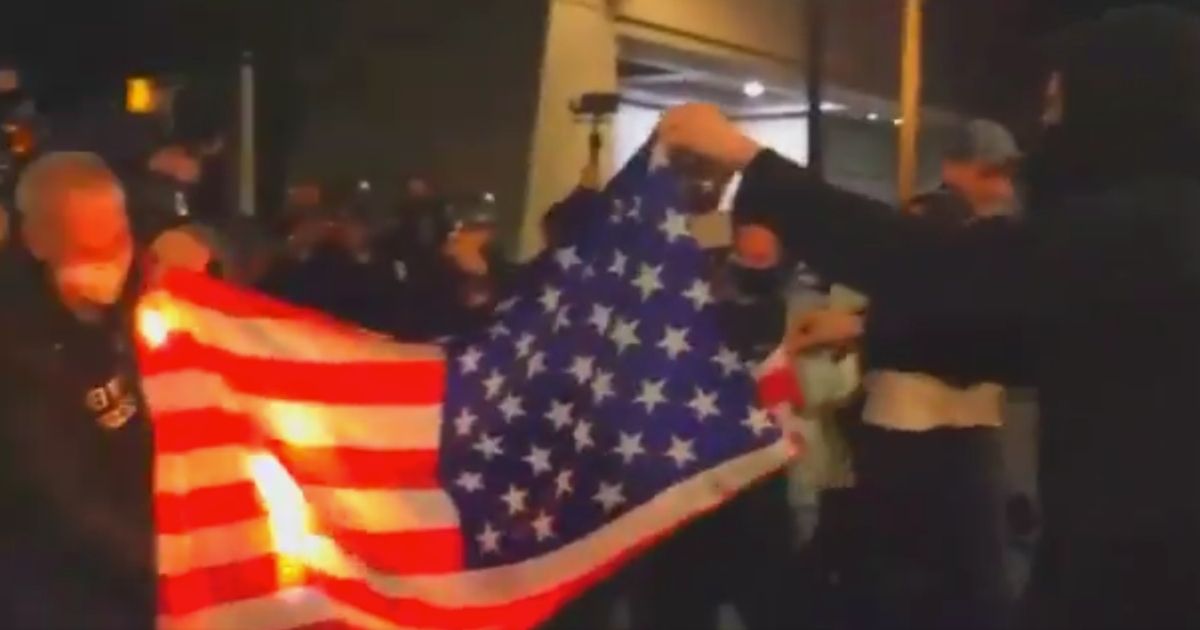 An American flag is burned by rioters