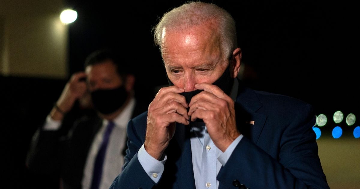Democratic presidential nominee Joe Biden adjusts his face mask as he arrives at New Castle Airport in New Castle, Delaware on Sept. 23, 2020.