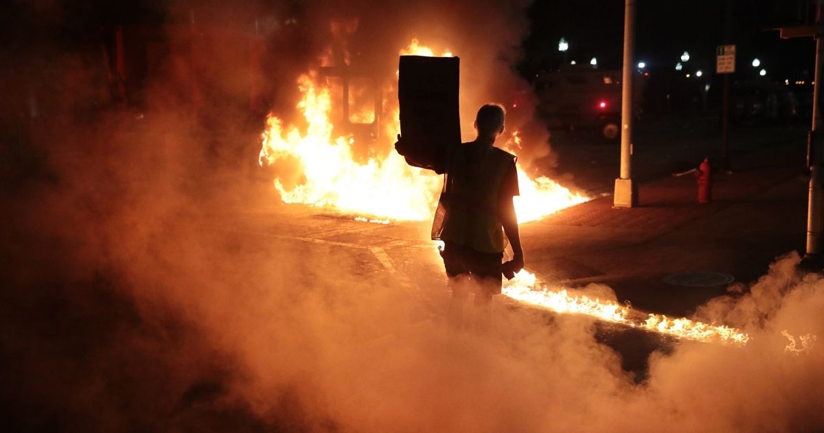Leaking diesel fuel from a burning garbage truck leaves a trail of fire in front of a protester during a second night of rioting on Aug. 24, 2020, in Kenosha, Wisconsin.