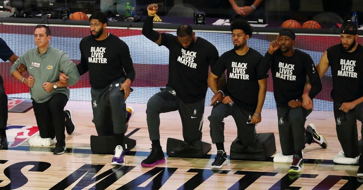 Los Angeles Lakers forward LeBron James raises a fist as he and teammates kneel during the national anthem before their game Aug. 8, 2020, in Lake Buena Vista, Florida.