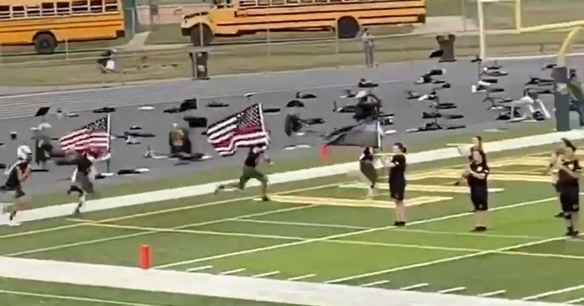 Players on the Little Miami High School football team run onto the field carrying flags in support of first responders.