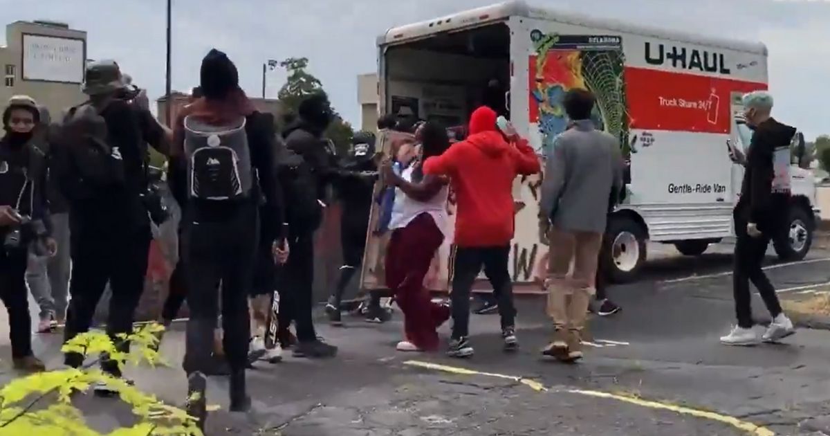 Demonstrators in Louisville, Kentucky, pick up signs and other items from the back of a U-Haul rental truck.