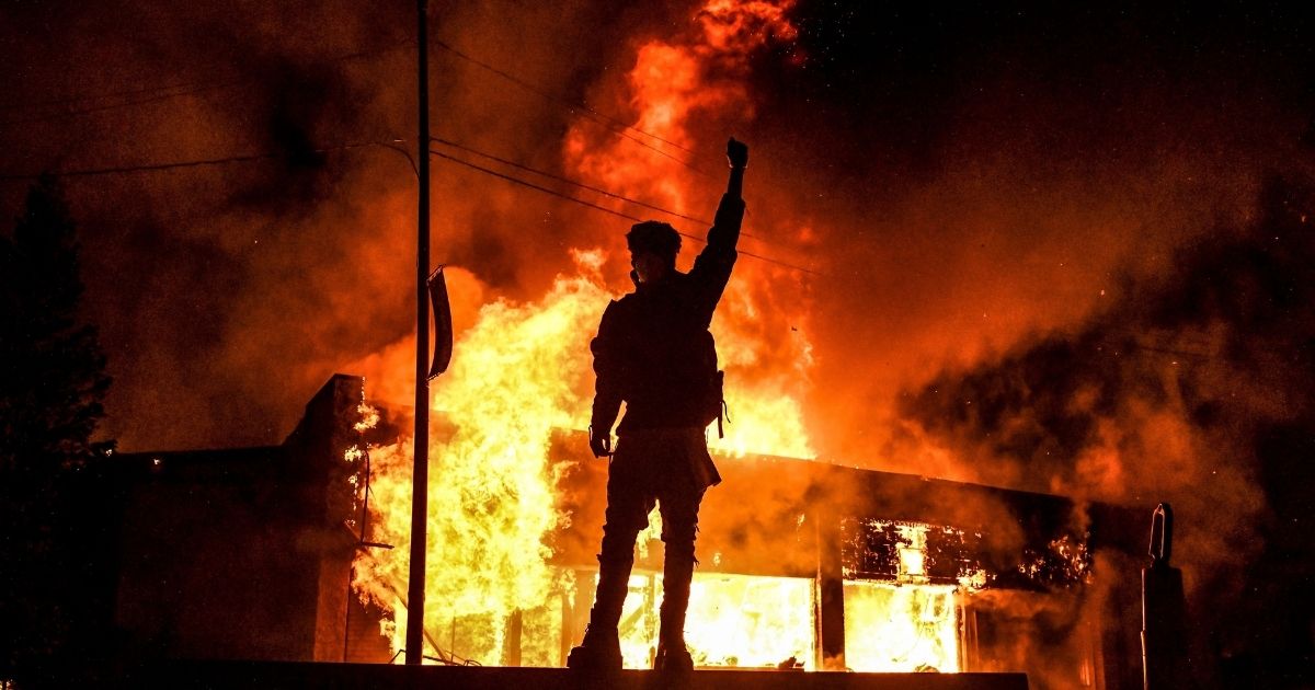 A protester reacts standing in front of a burning building set on fire during a riot in Minneapolis, Minnesota, on May 29, 2020.