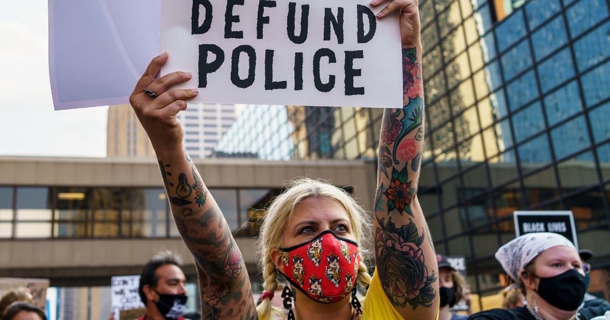 A woman holds a sign reading "Defund the Police" during a demonstration outside Hennepin County Government Plaza in Minneapolis on Aug. 24, 2020.