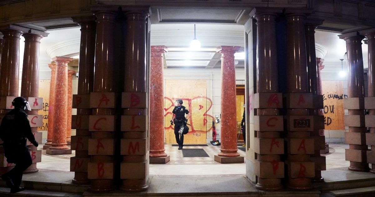 Police officers clear the lobby of City Hall in Portland, Oregon, after rioters vandalized the building Aug. 25, 2020.