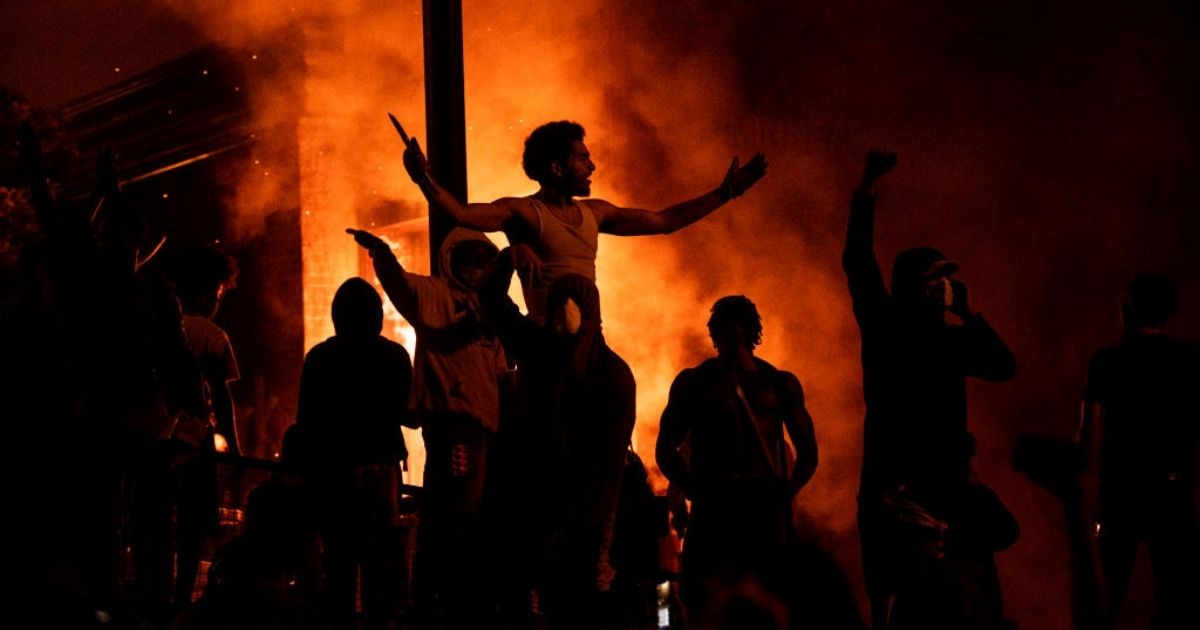Protesters cheer as the Third Police Precinct burns behind them on May 28, 2020, in Minneapolis.