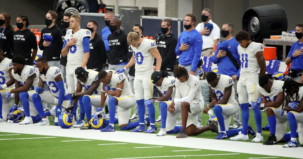 Jared Goff, left,, Cooper Kupp, center, and Josh Reynolds of the Los Angeles Rams stand while their teammates kneel in protest during the national anthem before their game against the Dallas Cowboys at SoFi Stadium in Inglewood, California on Sept. 13, 2020.