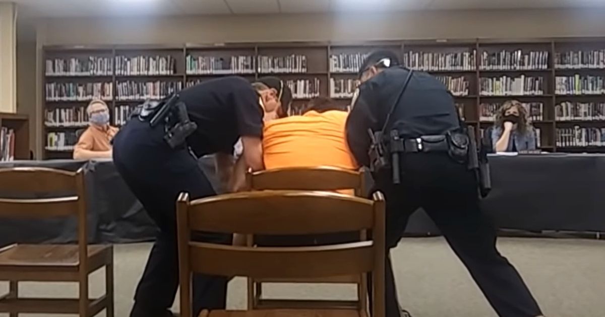 Police officers remove Reed Bender from a school board meeting in Mitchell, South Dakota, because he refused to wear a mask.