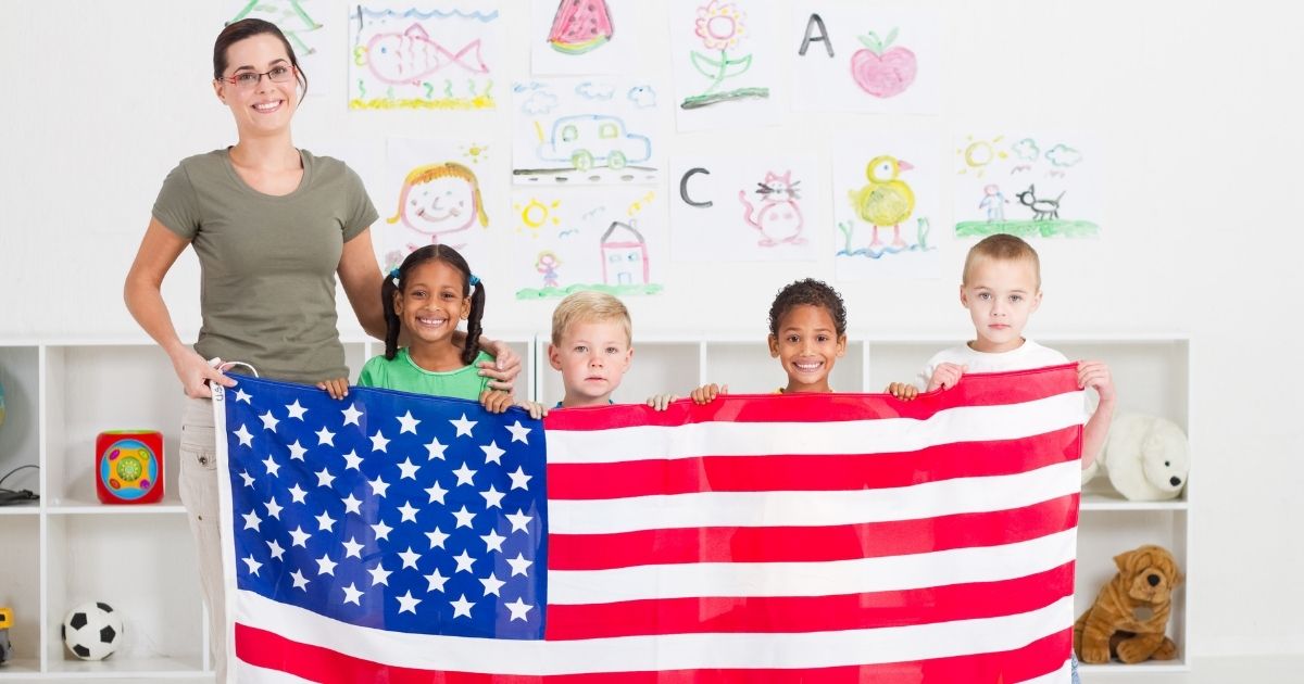 Schoolchildren and their teacher hold an American flag.