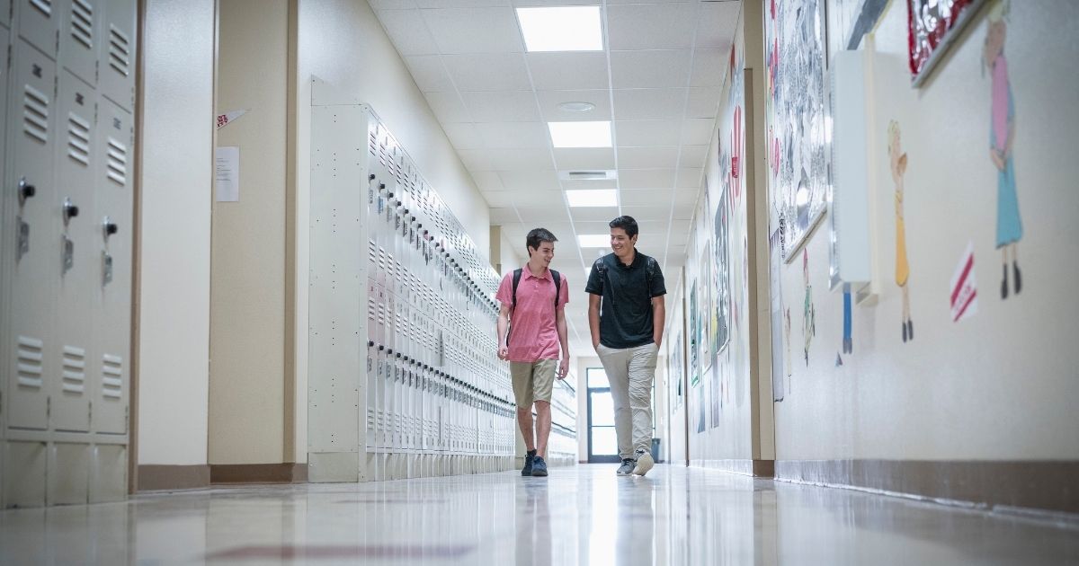 Two boys walk through the hall at a high school, as seen in the stock photo above.