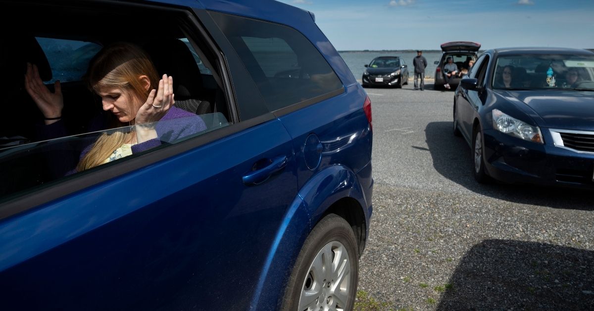 A member of Jesus' Church prays in the back seat of a car during a Sunday church service held at Great Marsh Park in Cambridge, Maryland, on March 22, 2020. - Pastor Abraham Lankford, who leads Jesus' Church secured the site after concerns over the new coronavirus prompted orders from state government to limit gatherings to less than 10 people. Across the globe an estimated 900 million people are confined to their homes, according to an AFP tally. The majority are hemmed in by obligatory government lockdown orders while others are under curfew, in quarantine or following advice not to leave their homes. In the US more than a third of the population are adjusting to life in various phases of lockdown.
