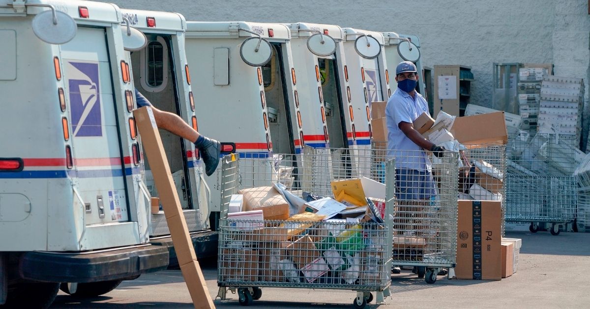 Postal workers sort, load and deliver mail as protesters hold a "Save the Post Office" demonstration outside a United States Postal Service location in Los Angeles on Aug. 22, 2020.