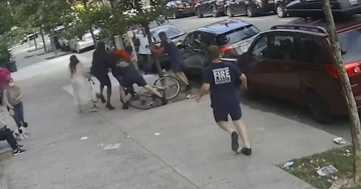 New York City firefighters tackle a man who allegedly punched a woman from his bicycle.
