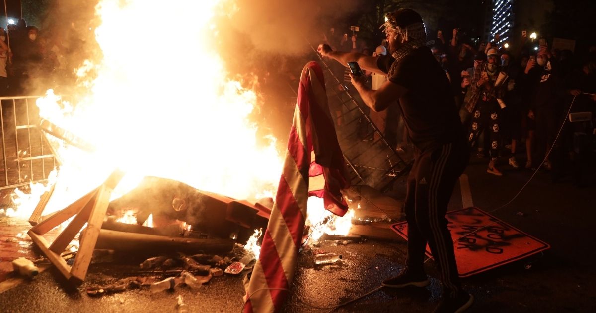 Demonstrators set a fire and burn an American flag during a protest near the White House on May 31, 2020, in Washington, D.C.