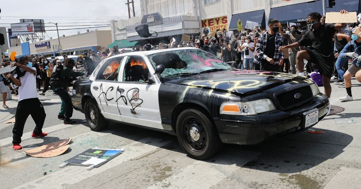 LOS ANGELES, CALIFORNIA - MAY 30: An LAPD vehicle begins to burn after being set alight by protesters during demonstrations following the death of George Floyd on May 30, 2020 in Los Angeles, California. Former Minneapolis police officer Derek Chauvin was taken into custody for Floyd's death. Chauvin has been accused of kneeling on Floyd's neck as he pleaded with him about not being able to breathe. Floyd was pronounced dead a short while later. Chauvin and 3 other officers, who were involved in the arrest, were fired from the police department after a video of the arrest was circulated.