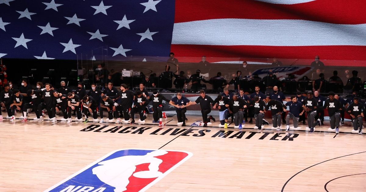 LAKE BUENA VISTA, FLORIDA - JULY 31: Players, coaches and staff kneel during the national anthem before the game between the Memphis Grizzlies and the Portland Trail Blazers at The Arena at ESPN Wide World Of Sports Complex on July 31, 2020 in Lake Buena Vista, Florida. NOTE TO USER: User expressly acknowledges and agrees that, by downloading and or using this photograph, User is consenting to the terms and conditions of the Getty Images License Agreement.
