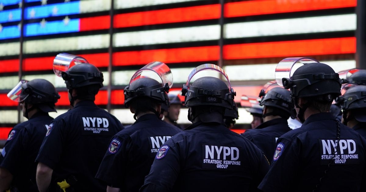 TOPSHOT - NYPD police officers watch demonstrators in Times Square on June 1, 2020, during a "Black Lives Matter" protest. - New York's mayor Bill de Blasio today declared a city curfew from 11:00 pm to 5:00 am, as sometimes violent anti-racism protests roil communities nationwide. Saying that "we support peaceful protest," De Blasio tweeted he had made the decision in consultation with the state's governor Andrew Cuomo, following the lead of many large US cities that instituted curfews in a bid to clamp down on violence and looting.