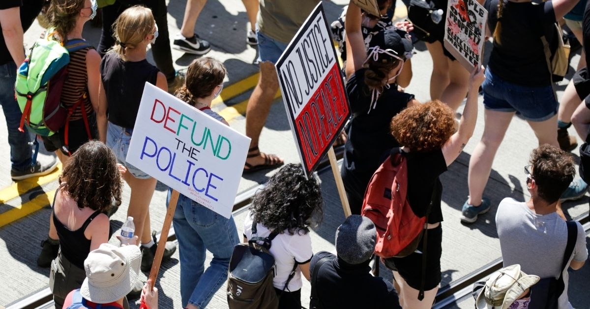 People carry signs during a "Defund the Police" march from King County Youth Jail to City Hall in Seattle, Washington on August 5, 2020.