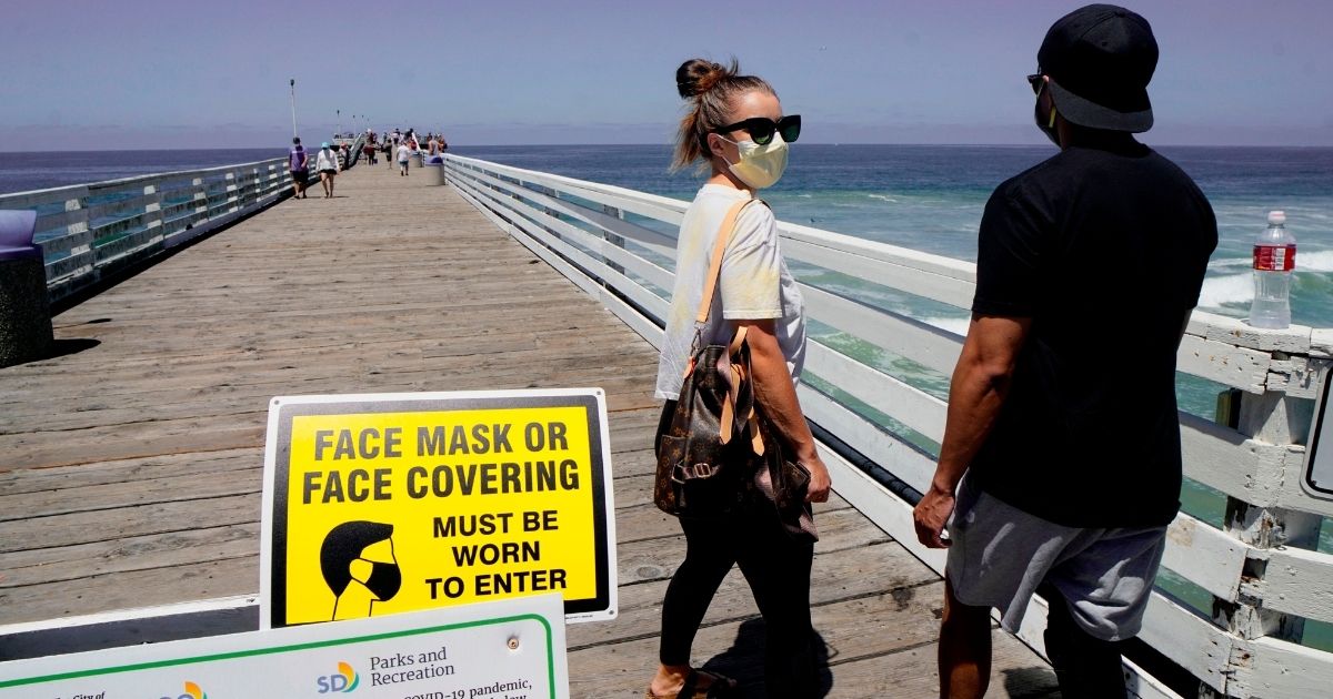 Beachgoers walk out onto the Pacific Beach Pier in San Diego, California on Saturday, July 4, 2020, amid the coronavirus pandemic. - Many beaches have been shut down for the Fourth of July weekend across California due to a resurgence of COVID-19. San Diego area beaches however have remained open.