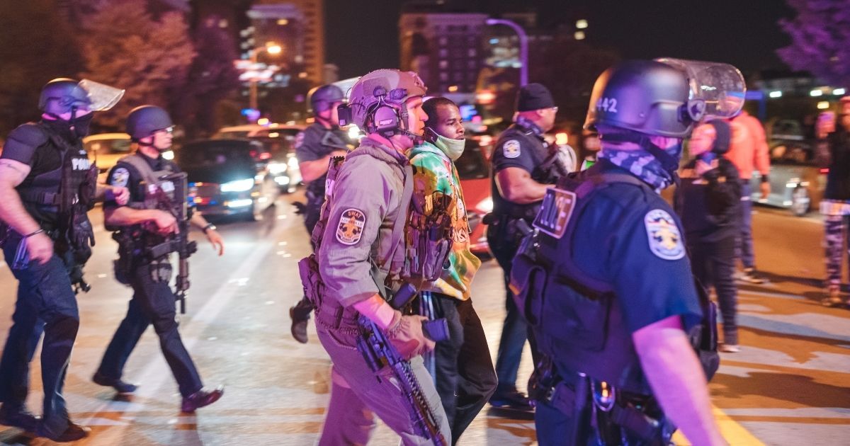 Police officers march a suspect into custody Wednesday amid rioting in Louisville, Kentucky.