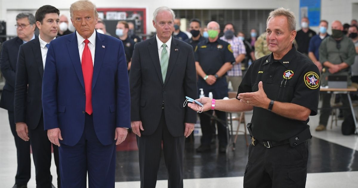 US President Donald Trump listens to Kenosha County Sheriff David Beth (R) on September 1, 2020, at Mary D. Bradford High School in Kenosha, Wisconsin. - Trump visited Kenosha, the city at the center of a raging US debate over racism, despite pleas to stay away and claims he is dangerously fanning tensions as a reelection ploy.