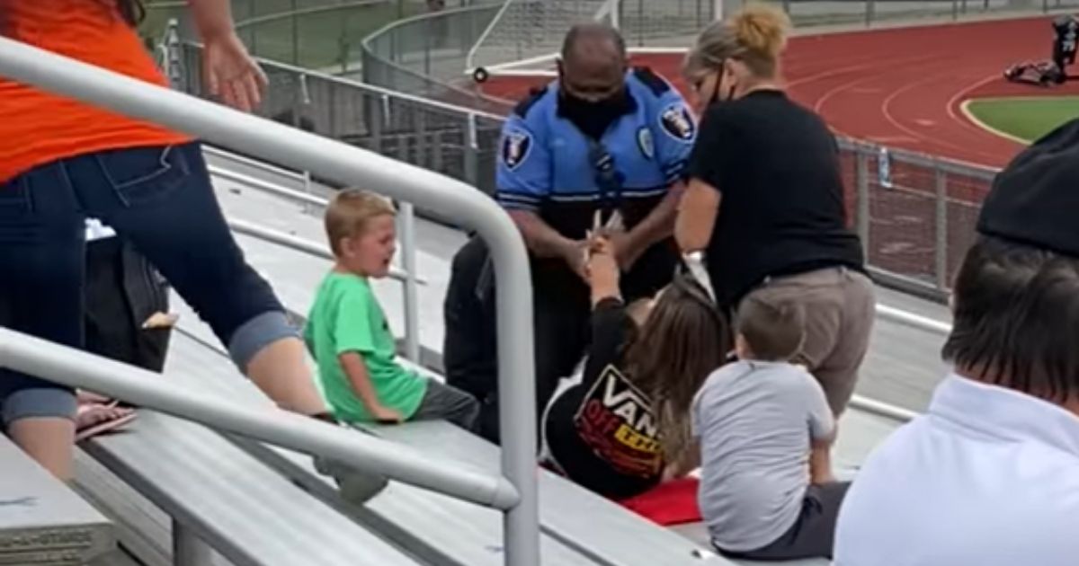 A Logan, Ohio, police officer arrests Alecia Kitts for not wearing a mask at a football game.