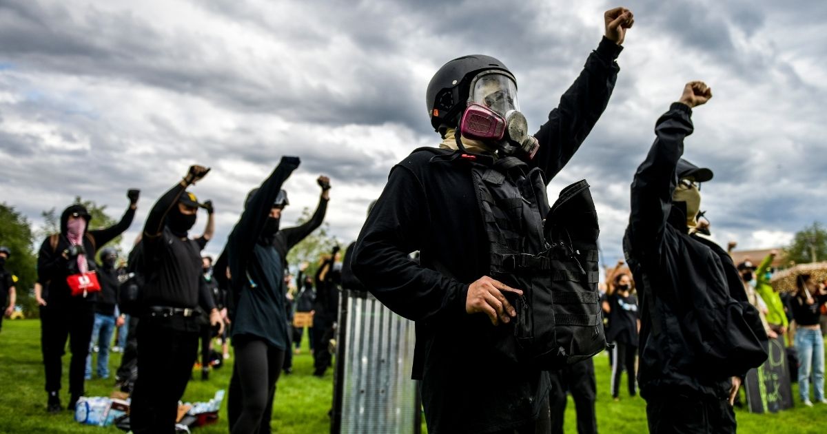 People raise their fists as they protest outside the Aurora Police Department headquarters on July 25, 2020, in Aurora, Colorado.