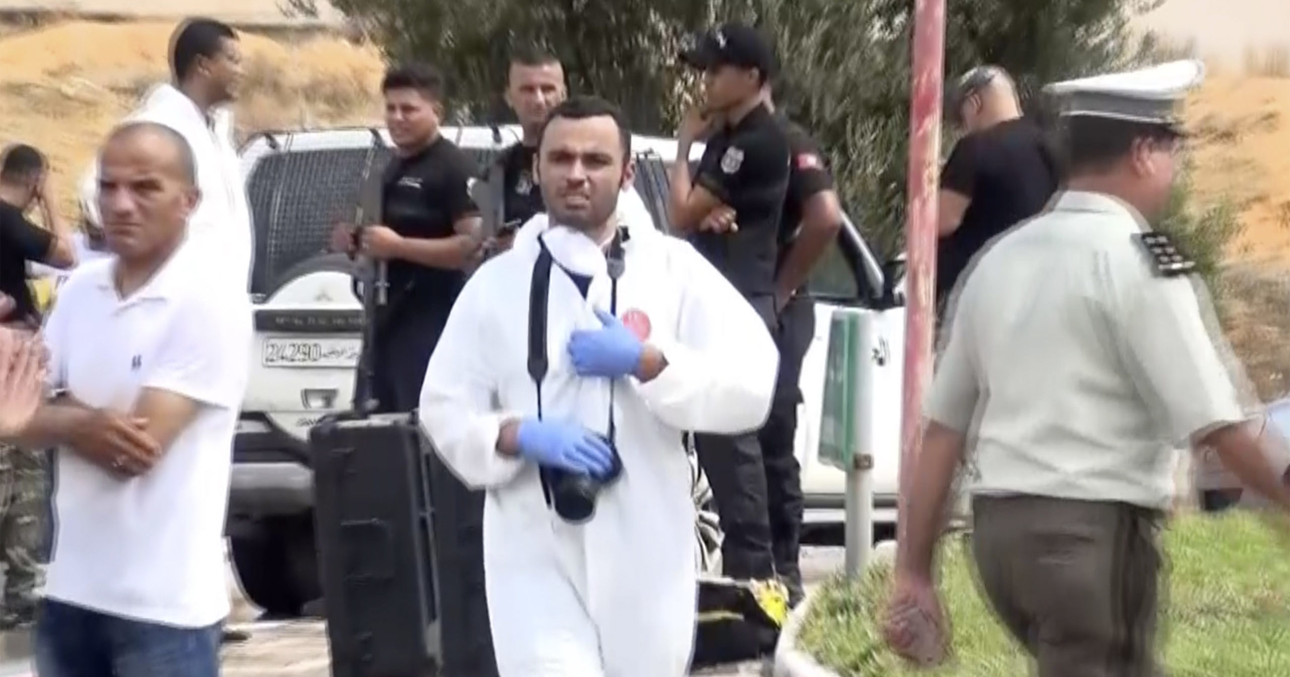 In this image taken from a video, Tunisian police officers investigate after Tunisian forces killed three suspected Islamic militants who rammed their vehicle into security officers and attacked them with knives, killing one and injuring another in the coastal resort town of Sousse, eastern Tunisia, on Sept. 6, 2020.