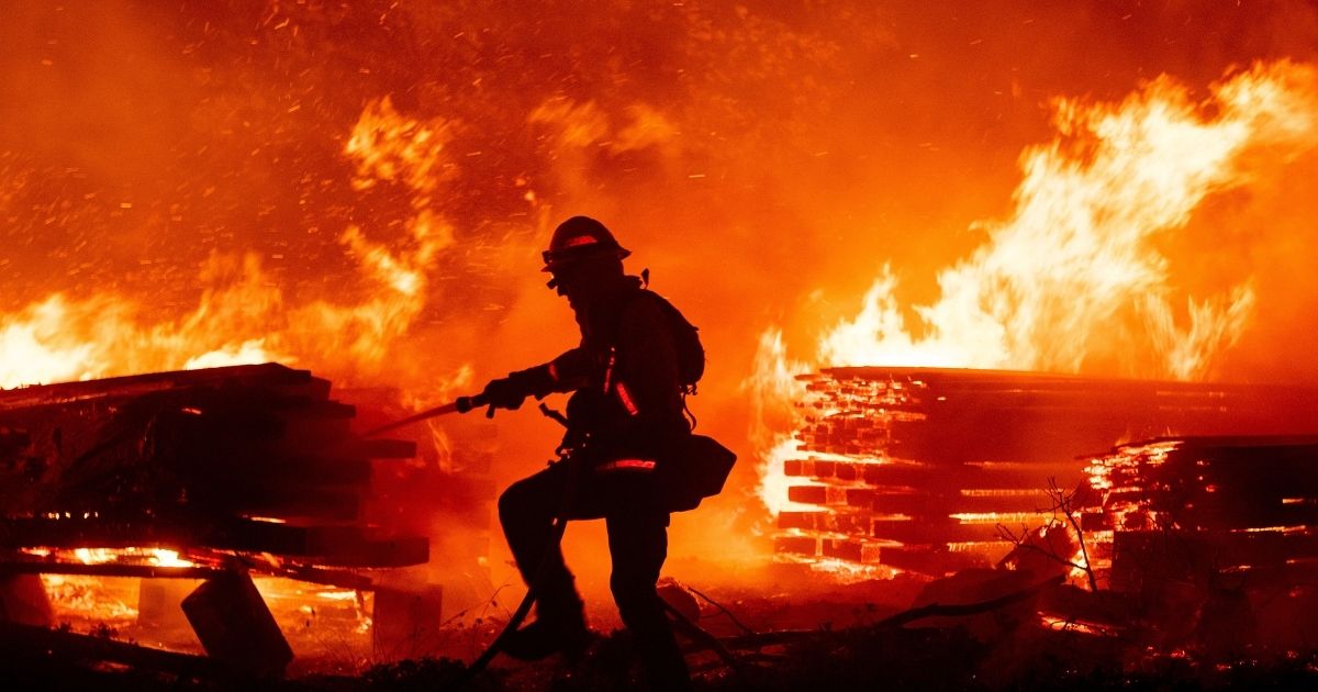 A firefighter douses flames in the Cascadel Woods area of unincorporated Madera County, California, on Sept. 7, 2020.