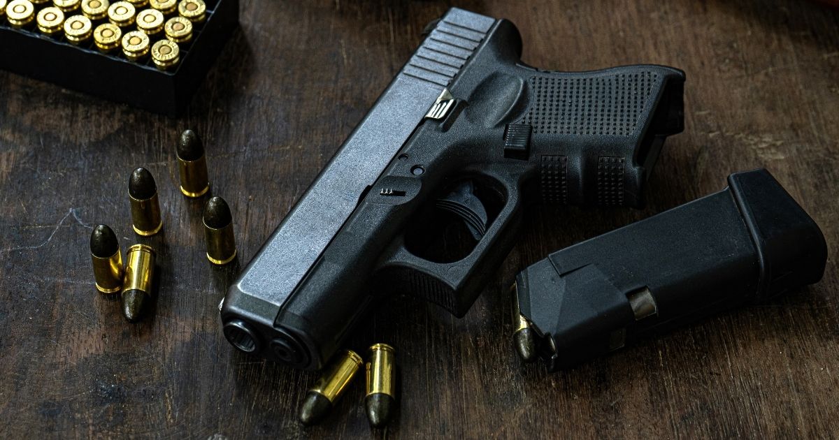 A gun rests on a table in the above stock image.