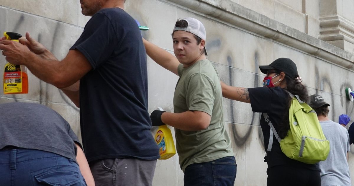 Volunteers, including Kyle Rittenhouse, center, clean graffiti from a high school near the Kenosha County Courthouse following another night of unrest on Aug. 25, 2020, in Kenosha, Wisconsin.
