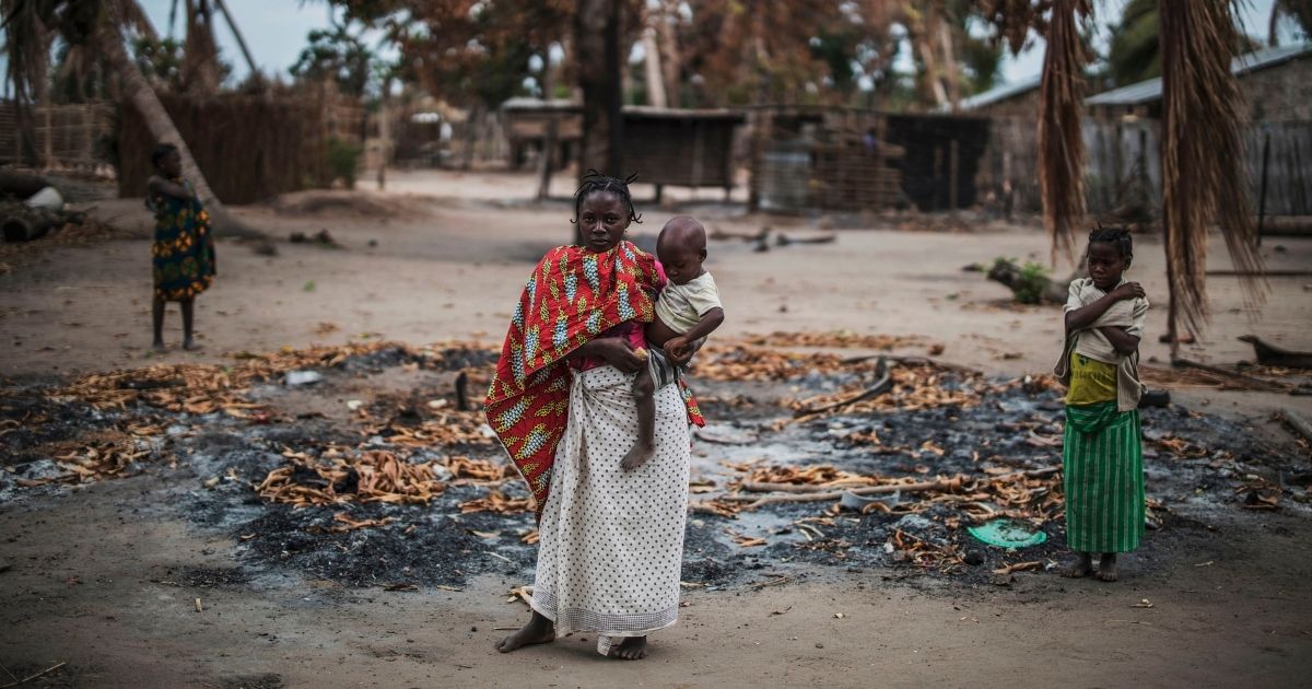 A woman holds her child in a burned area in a village after an attack by an Islamist group in the Macomia province of Mozambique on Aug. 24, 2019.