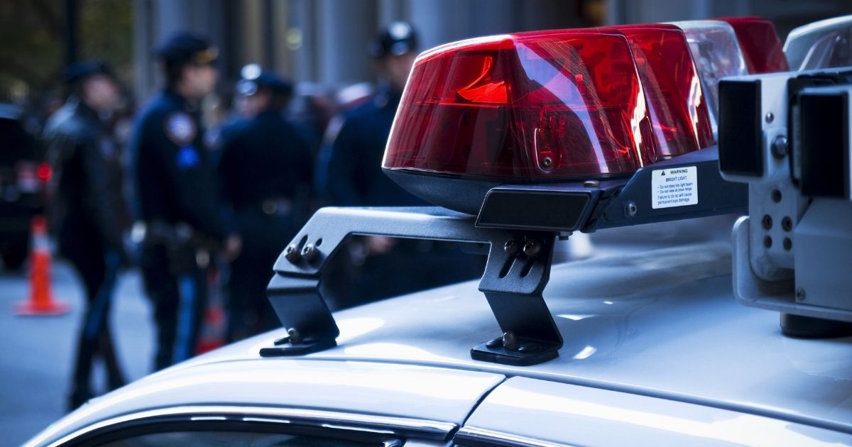 Police officers stand behind a vehicle in this stock image.