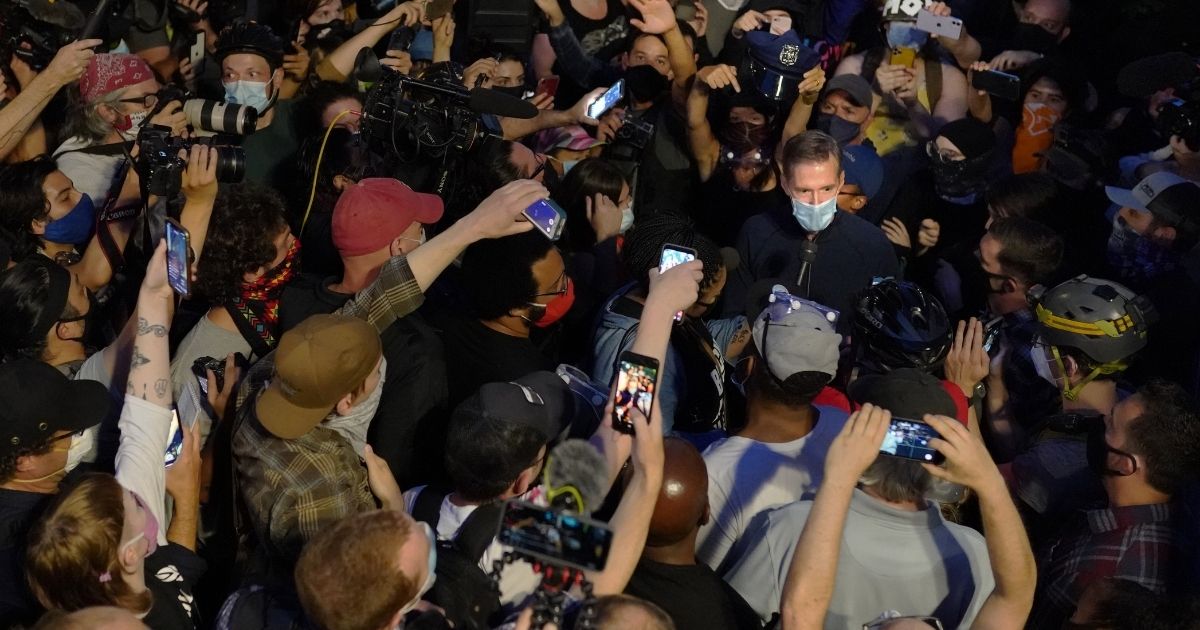 Portland Mayor Ted Wheeler speaks to the media while surrounded by protesters on July 22, 2020, in Portland, Oregon.