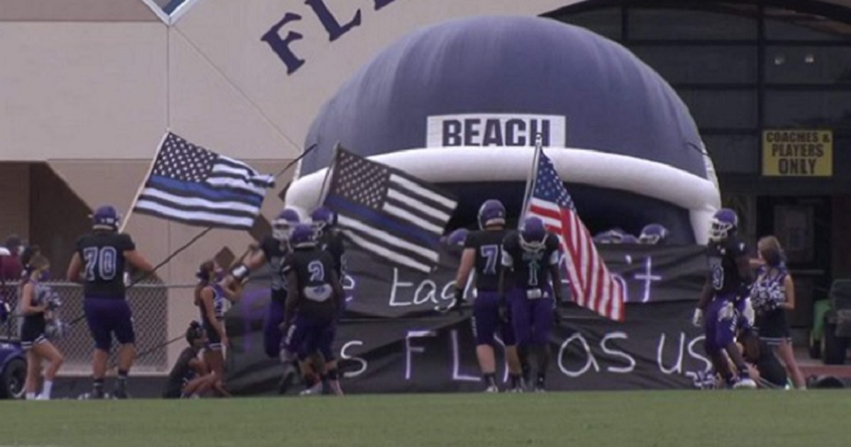 Players for the Fletcher High School in Neptune Beach, Florida, carry Thin Blue Line flags onto the field in a pre-game ceremony.