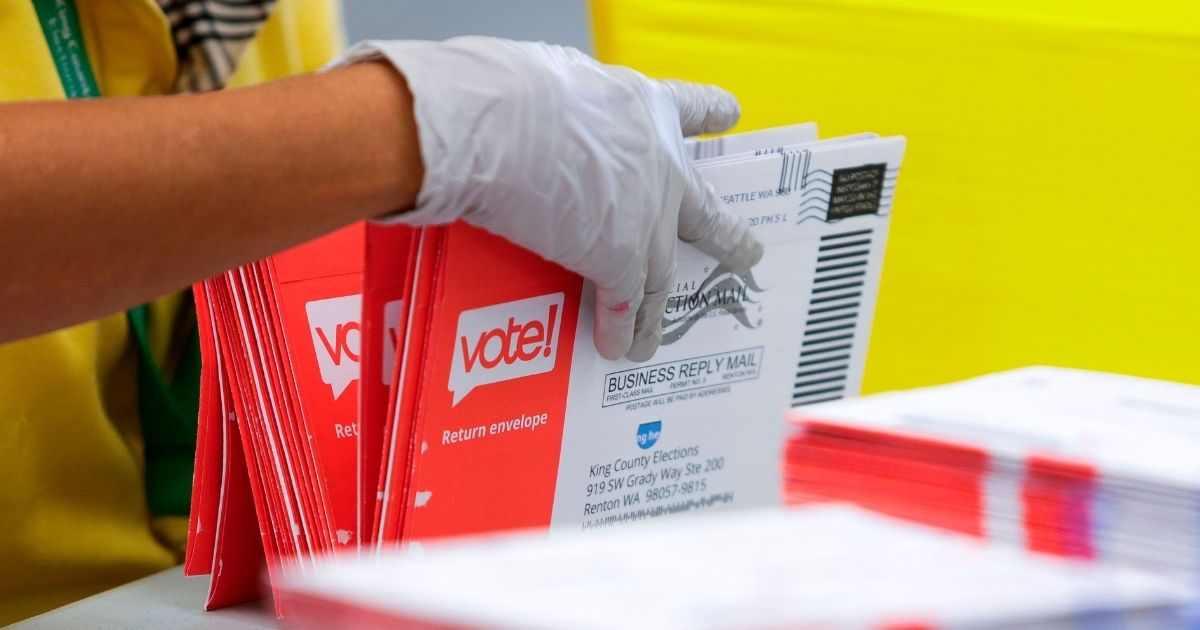 An election worker opens envelopes containing mail-in ballots for the Washington state primary in Renton, Washington, on Aug. 3, 2020.