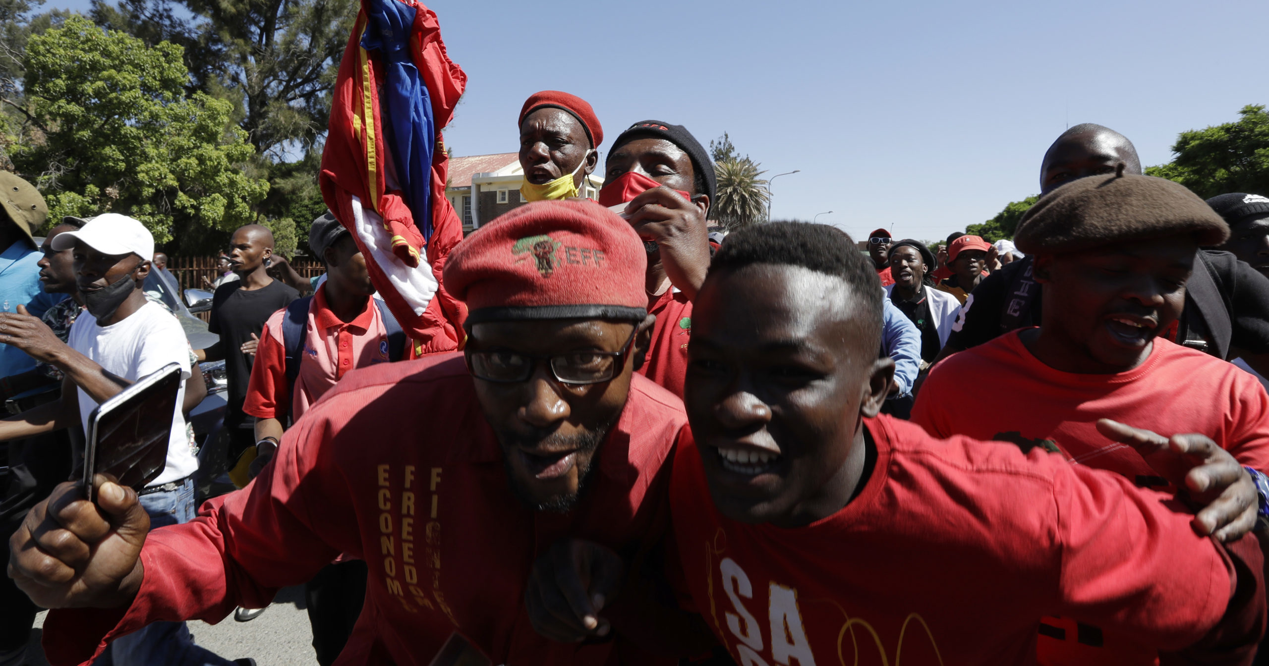 Members of the Economic Freedom Fighters protest Friday outside the magistrates court in Senekal, South Africa, where two suspects were to appear on charges of killing a white farmer.